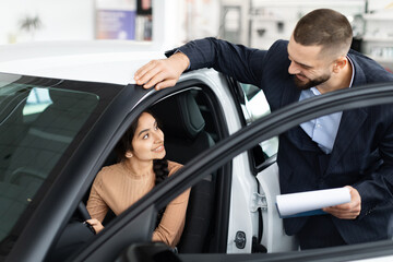 Fototapeta na wymiar Salesman explaining car features to a woman