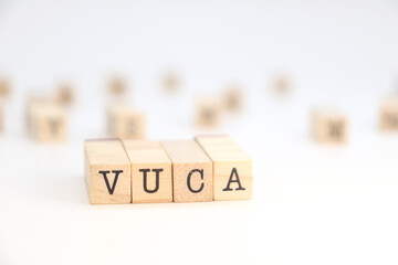 word VUCA (Volatility, Uncertainty, Complexity, Ambiguity) written on wooden cubes on a white...