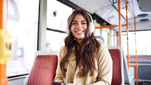 Happy Spanish woman enjoying music in a city bus