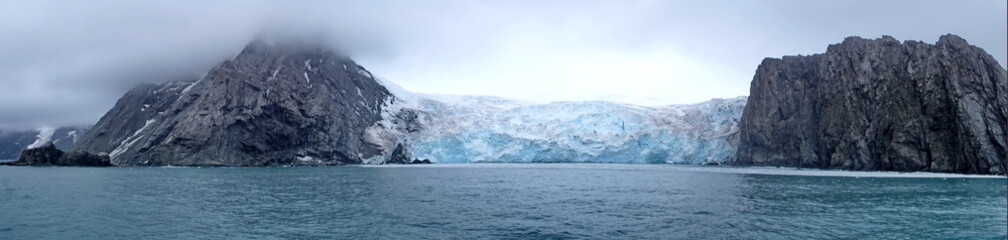 Panorama of a glacier meeting the ocean between two mountains, on Elephant Island, Antarctica