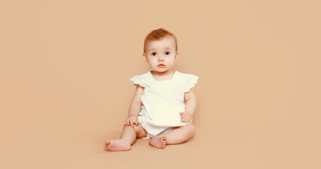 Portrait happy cute baby crawling on the floor on brown studio background
