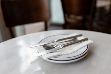 Closeup on ceramic two plates with stainless steel fork and knife prepared for dinner. Dishware...