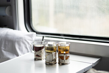 three glasses of tea on the table in the train compartment near the window