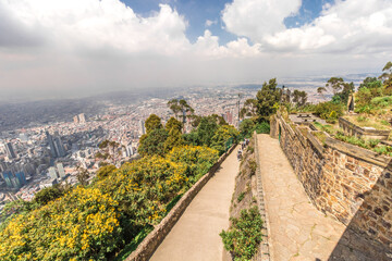 Horizontal landscape shot of the city of Bogota in Colombia from Monserrate Hill on a sunny summer day with clouds and some vegetation