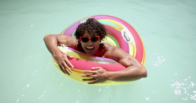 Biracial man enjoys pool time with colorful float at home
