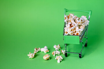 Freshly made popcorn in a shopping cart on green background
