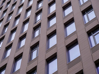 Angular view of a contemporary building showcasing repetitive pattern of windows and textured cladding.