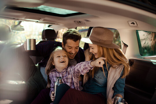 Happy family with a child drinking from thermos cups on a road trip