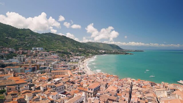 Aerial view of Cefalu, Sicily, Italy. Cinematic drone shot of famous travel destination. Slow drone shot travelling forward. View of seafront city and beach
