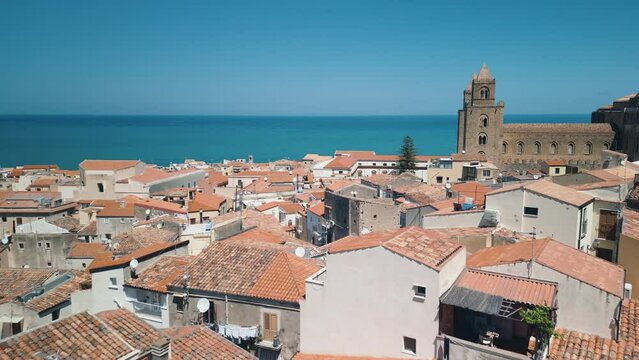 Aerial view of Cefalu, Sicily, Italy. Cinematic drone shot of famous travel destination. Slow drone shot travelling forward at low altitude. View of Cefalu Cathedral and city seafront