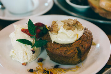 muffin carrot cake with cream topping and icecream on the side 