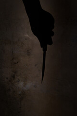 the shadow of a hand holding a knife on a dirty wall