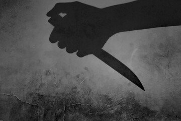 the shadow of a hand holding a knife on a dirty wall
