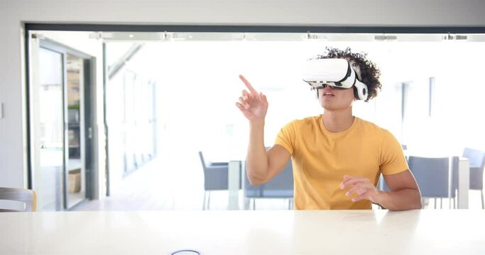 A young biracial man is using a virtual reality headset with copy space at home in the kitchen