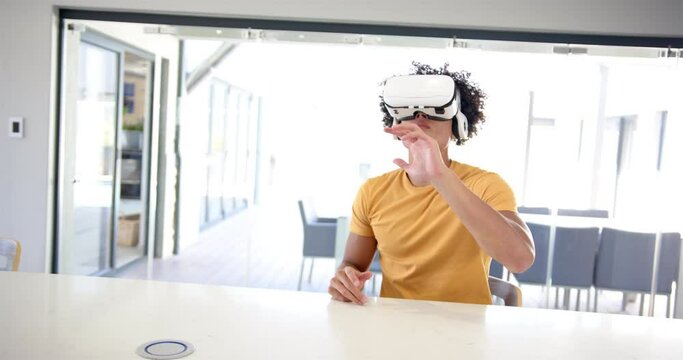 A young biracial man is using virtual reality goggles at home in the kitchen, white background