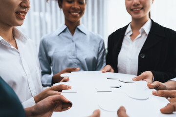 Diverse corporate officer workers collaborate in office, connecting puzzle pieces to represent...