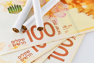 Cigarettes are on 100 shekel bills. Concept of big expenses, big price or taxes.
