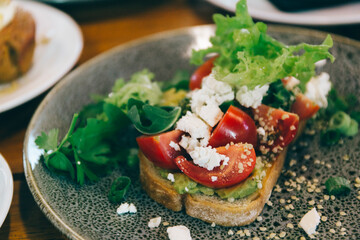 avocado on toast with tomato, feta cheese, lettuce on the top