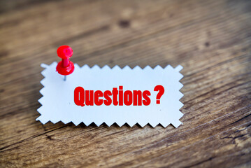 Questions note pinned on wooden background 
