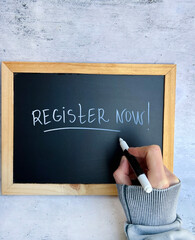 Hand writing register now on a chalkboard 