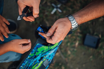 Close up of male's and boy's hands repairing car toy with tools.