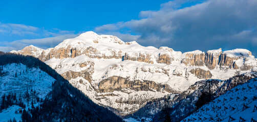 Dolomites in Italy. Sella mountain massif and mountain range at rising sun in March, covered with snow. Panoramic view from Pieve di Livinalogo near Arabba, famous ski and snowboard resort - 768235661