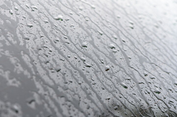 Rainy day, water droplets on car window's side mirror.
