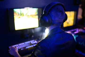 Back view of a bald woman gamer playing online video games and streaming it