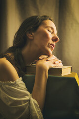 woman in a white blouse with a Carmen neckline with her hands resting on an old book in a romantic attitude II