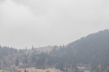 Obraz premium Yasinya, Ukraine. March 17, 2024, early spring, cloudy rainy sky. an incredibly beautiful view of the fog-shrouded mountains. small village houses in which people live.