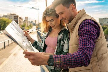 young couple uses paper map to explore city, tourists on vacation in european city