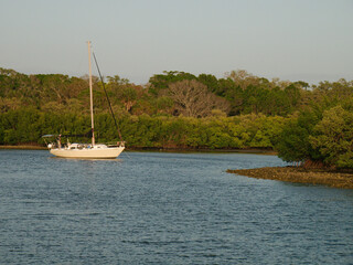 Wide View out at calm water with reflections and green trees on sides, blue and white sky. White...