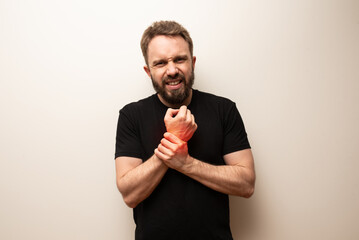 Wrist pain problem concept: bearded hipster middle aged man holds his wrist