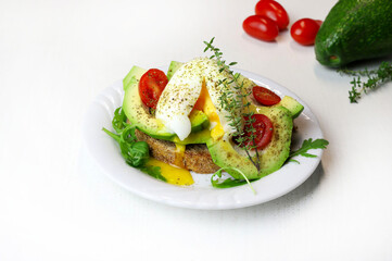 Toast di avocado con uovo in camicia e pomodoro su sfondo bianco. Concetto di cibo sano. Vista dall'alto. - 768243065