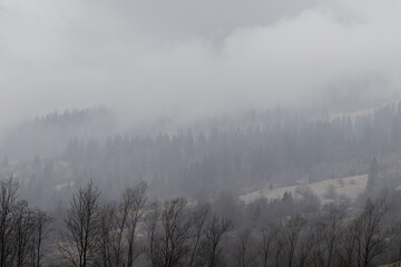 Yasinya, Ukraine. March 17, 2024, early spring, cloudy rainy sky. an incredibly beautiful view of the fog-shrouded mountains. small village houses in which people live.