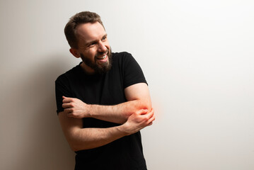 Elbow pain joint problem: middle aged bearded hipster man holds his elbow joint in pain
