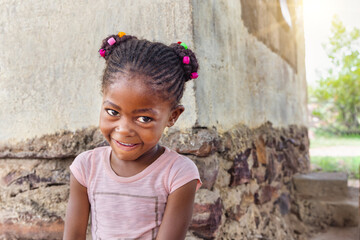 african girl with braids and a naughty look on her face in front of the house, village life