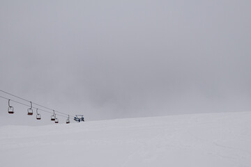 Dragobrat, Ukraine. March 18, 2024. In the morning, the village was heavily covered with snow. everything was covered in thick fog, but people continued to ski and climb the mountains on lifts.