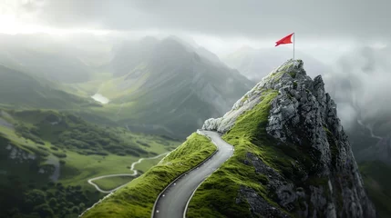 Fotobehang Red flag atop rocky mountain peak with curving road among green valleys, adventure and destination concept © Andrey