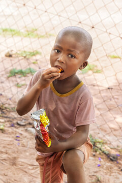 hungry young african child eating snacks, village life in a remote area