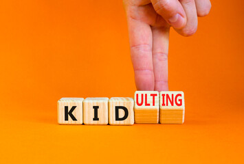 Kid or kidulting symbol. Concept words Kid or Kidulting on wooden cubes. Beautiful orange table orange background. Psychologist hand. Healthy lifestyle and kid or kidulting concept. Copy space.