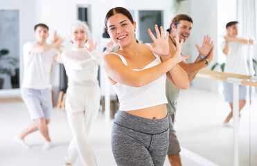 Fototapeta premium Cheerful young and adult men and women training in dance fitness studio. Aerobic class for adults.
