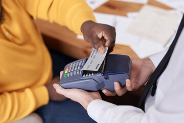 High angle closeup of unrecognizable African American man paying for lunch in restaurant using...