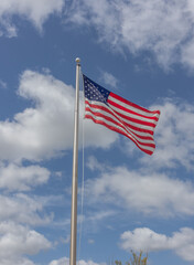 American flag waving against blue sky with white clouds