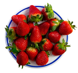 There is plate on table filled with ripe red strawberries. Fresh berries with green tails. Isolated over white background