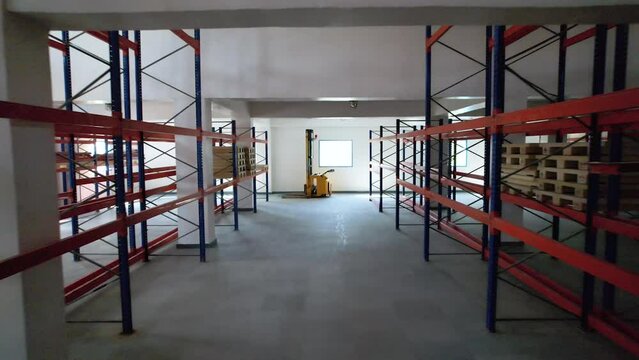 fully empty warehouse area with colored racks for storage and epoxy flooring in a pharmaceutical manufacturing factory for active pharma ingredients, speciality chemicals, hazardous chemical	