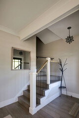 A corner staircase with black spindles ascends elegantly, contrasting with light walls in a traditional cottage.