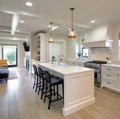 Bright white kitchen with island and three chairs, bathed in warm light, inviting for gatherings...