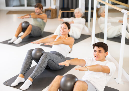Group of different people performs sports exercises in fitness center