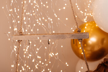 A wooden swing decorated with festive lights and golden balloons, creating a dreamy holiday...
